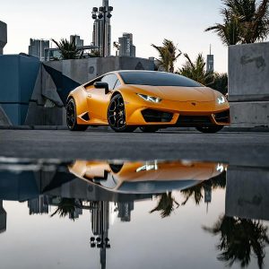 Striking image of a luxury Lamborghini with its reflection in an urban cityscape, showcasing elegance and speed.